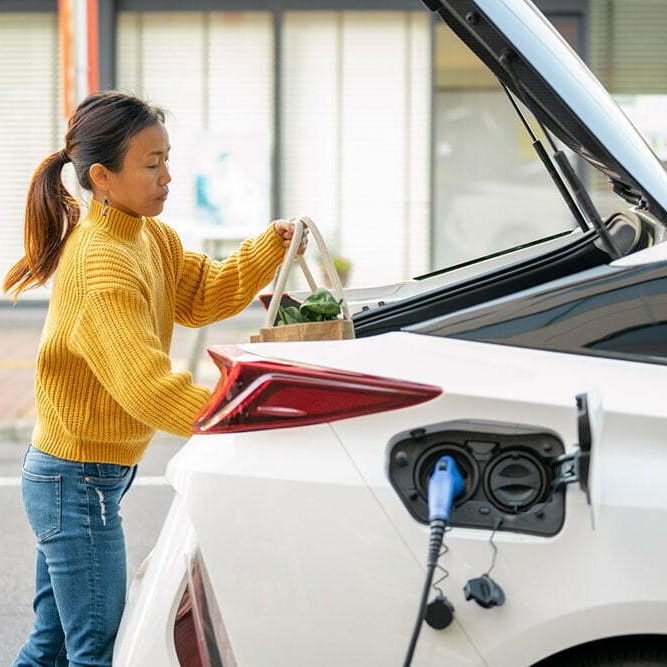 Woman-load-shopping-into-EV-behind-recharged